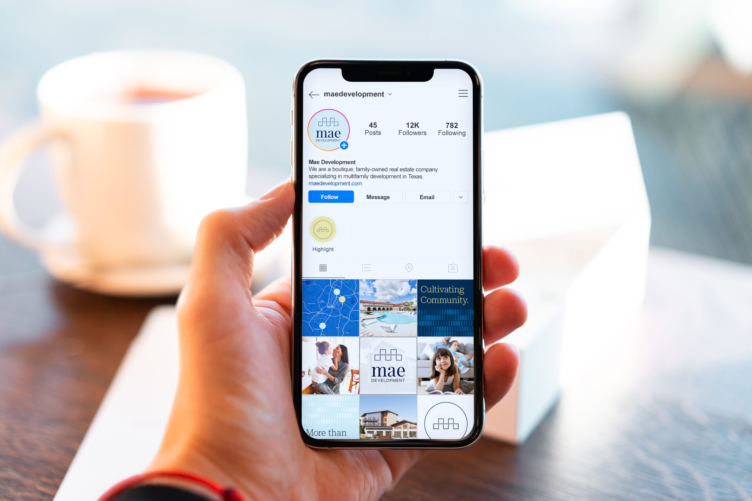 A person holds a smartphone displaying the Instagram profile of "maedevelopment" with profile details and image posts visible on the screen.