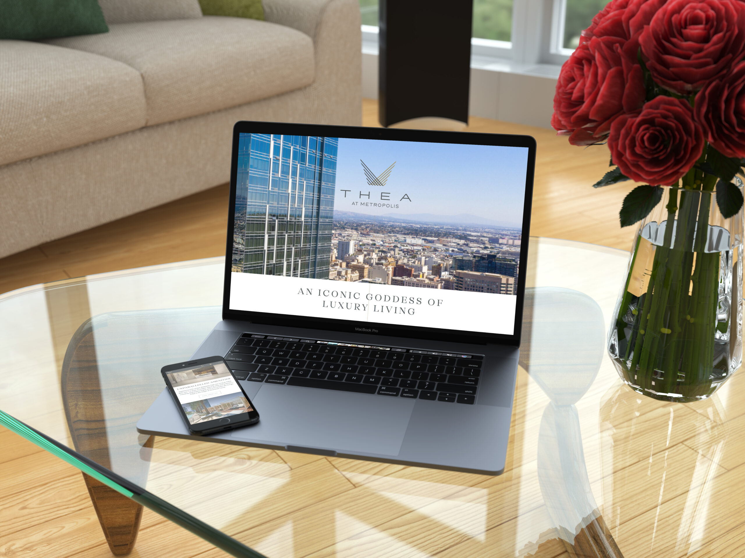 A laptop and smartphone on a glass table display a website for "Thea at Metropolis," near a vase of red roses in a modern living room with large windows.