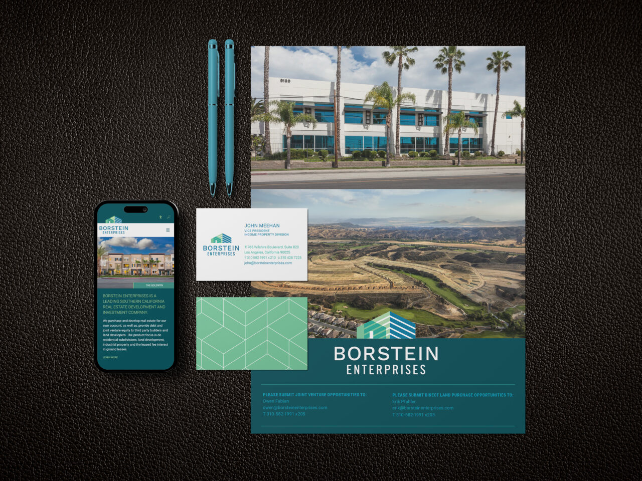 A flat lay of Borstein Enterprises branded materials, including a website on a phone, business card, letterhead, two pens, and photos of a building and a landscape, on a black textured surface.