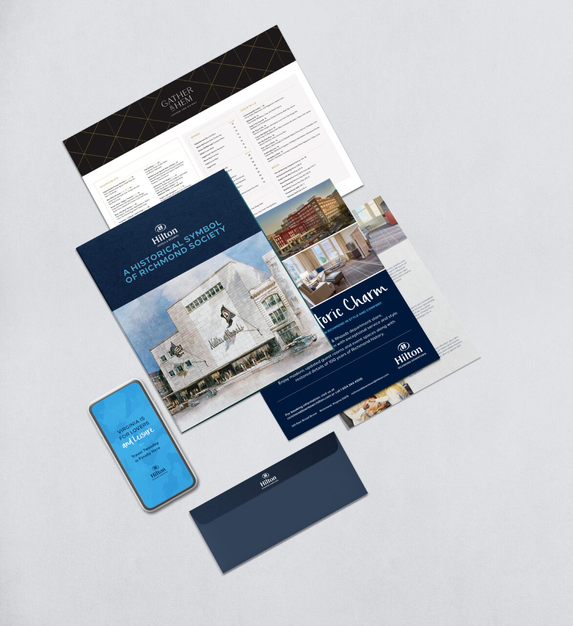 A collection of Hilton Hotel marketing materials, including brochures, a menu, a phone screen mockup, and an envelope, arranged on a light gray surface.