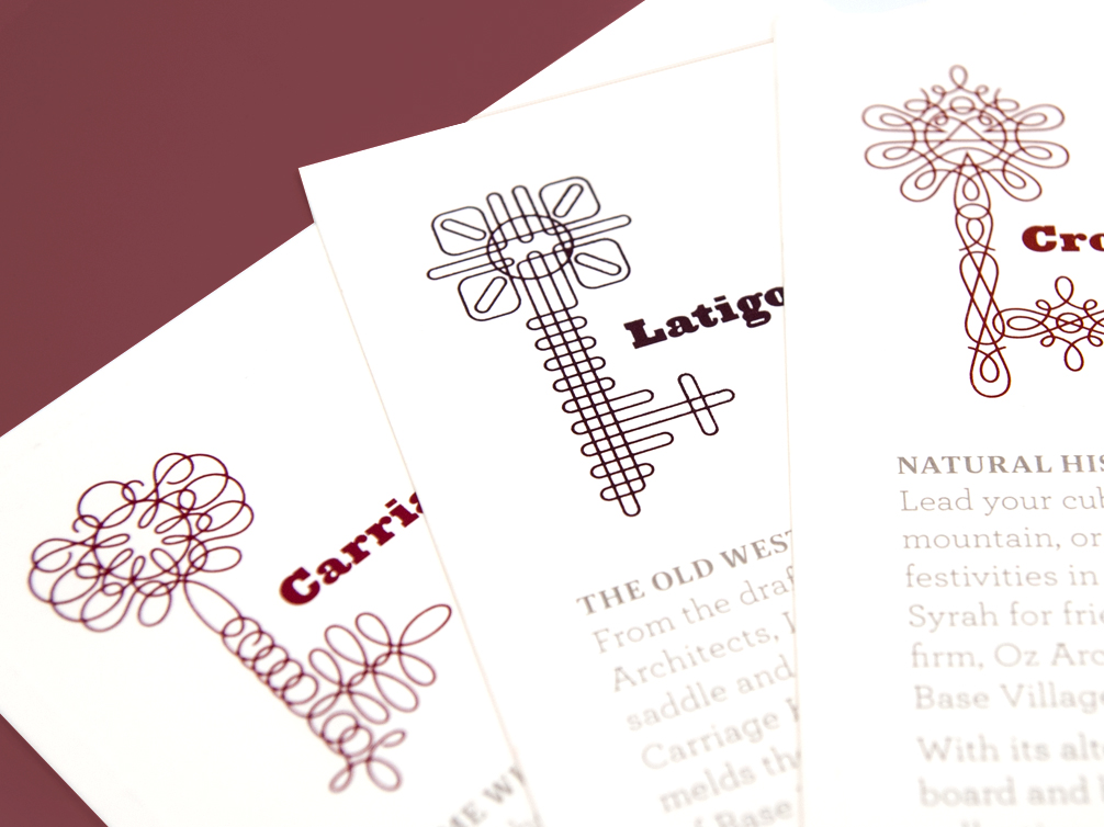 Three white cards with intricate, abstract key illustrations and partially visible text, arranged in a fanned-out display on a maroon surface.