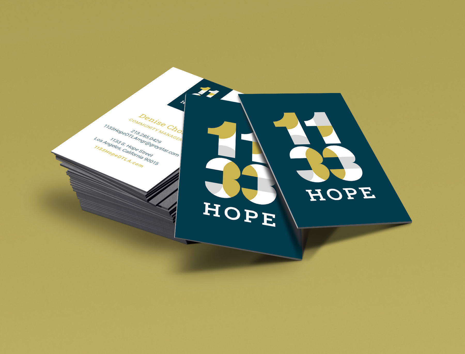 A stack of business cards on a yellow surface, featuring the text "1133 HOPE" in bold on the front and contact information on the back.