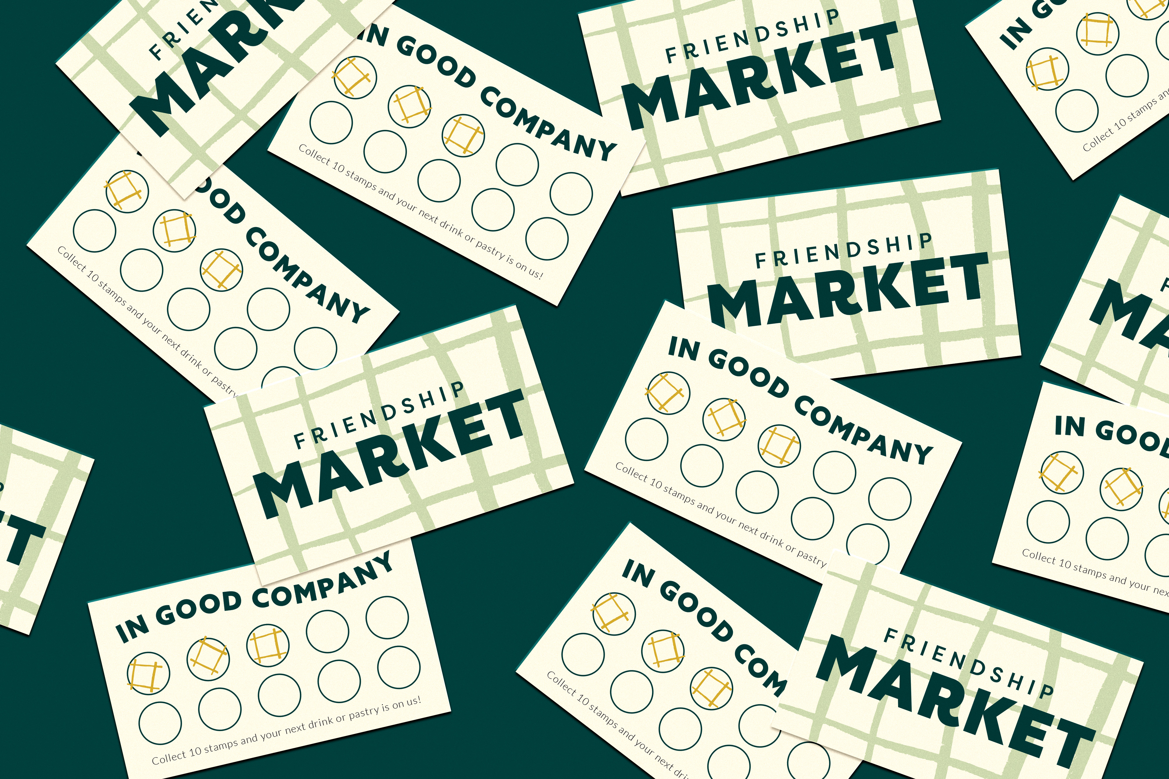 Several cards labeled "Friendship Market" and "In Good Company" with circular stamp areas and cube icons are scattered on a dark green surface.