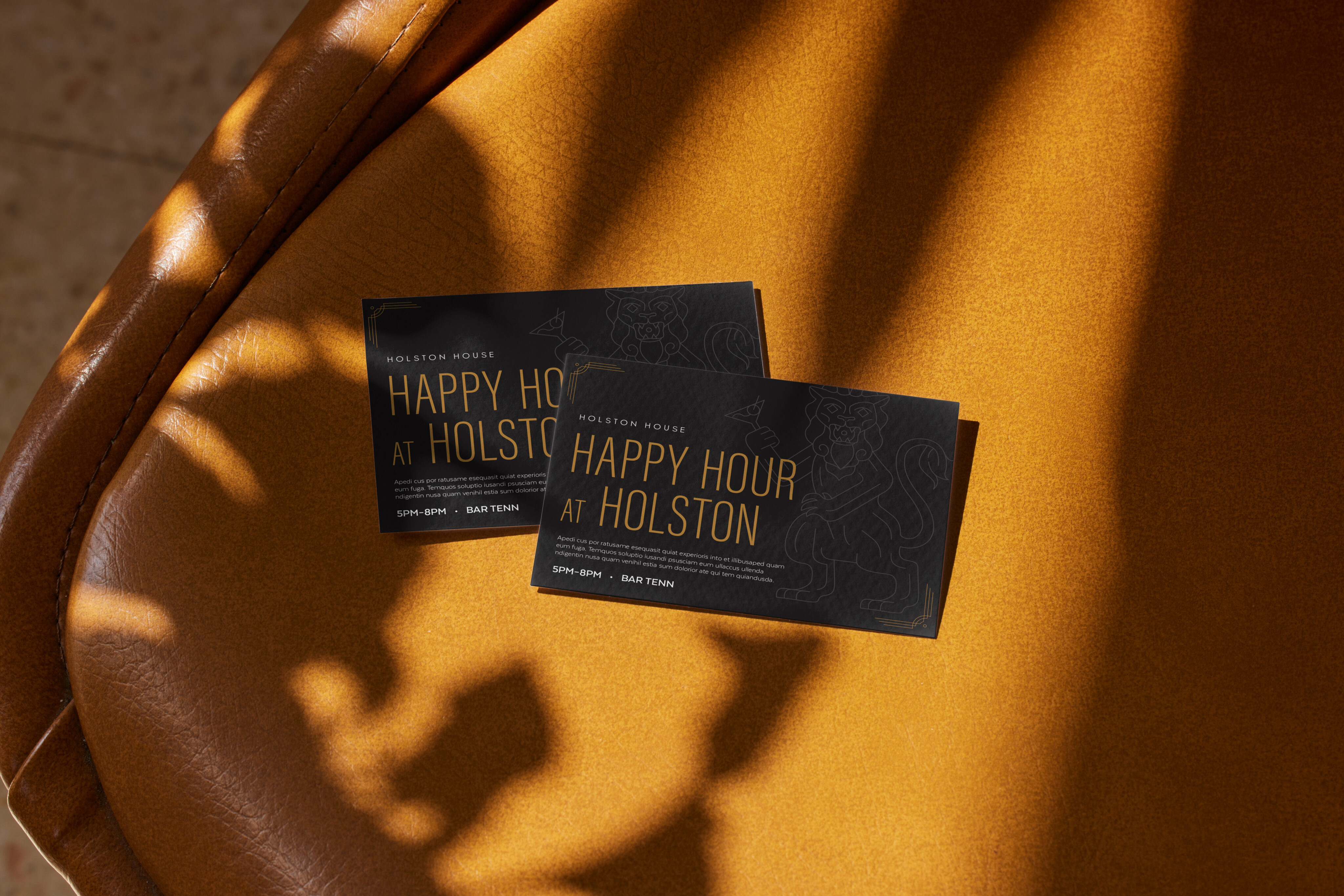Two "Happy Hour at Holston" cards rest on a tan leather seat with sunlight casting shadows across the surface.