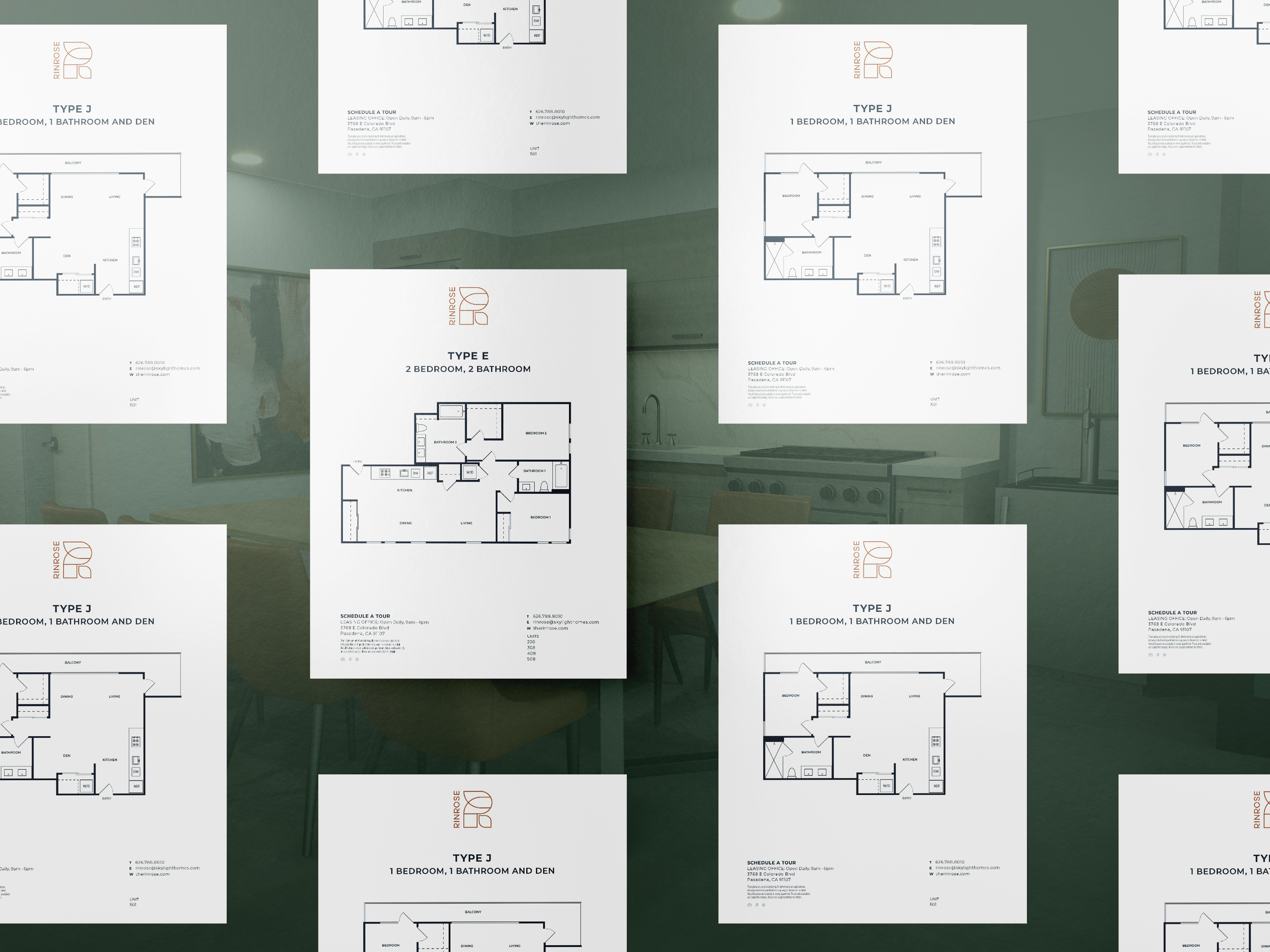 Multiple floor plan sheets are displayed on a reflective surface with a kitchen visible in the background.