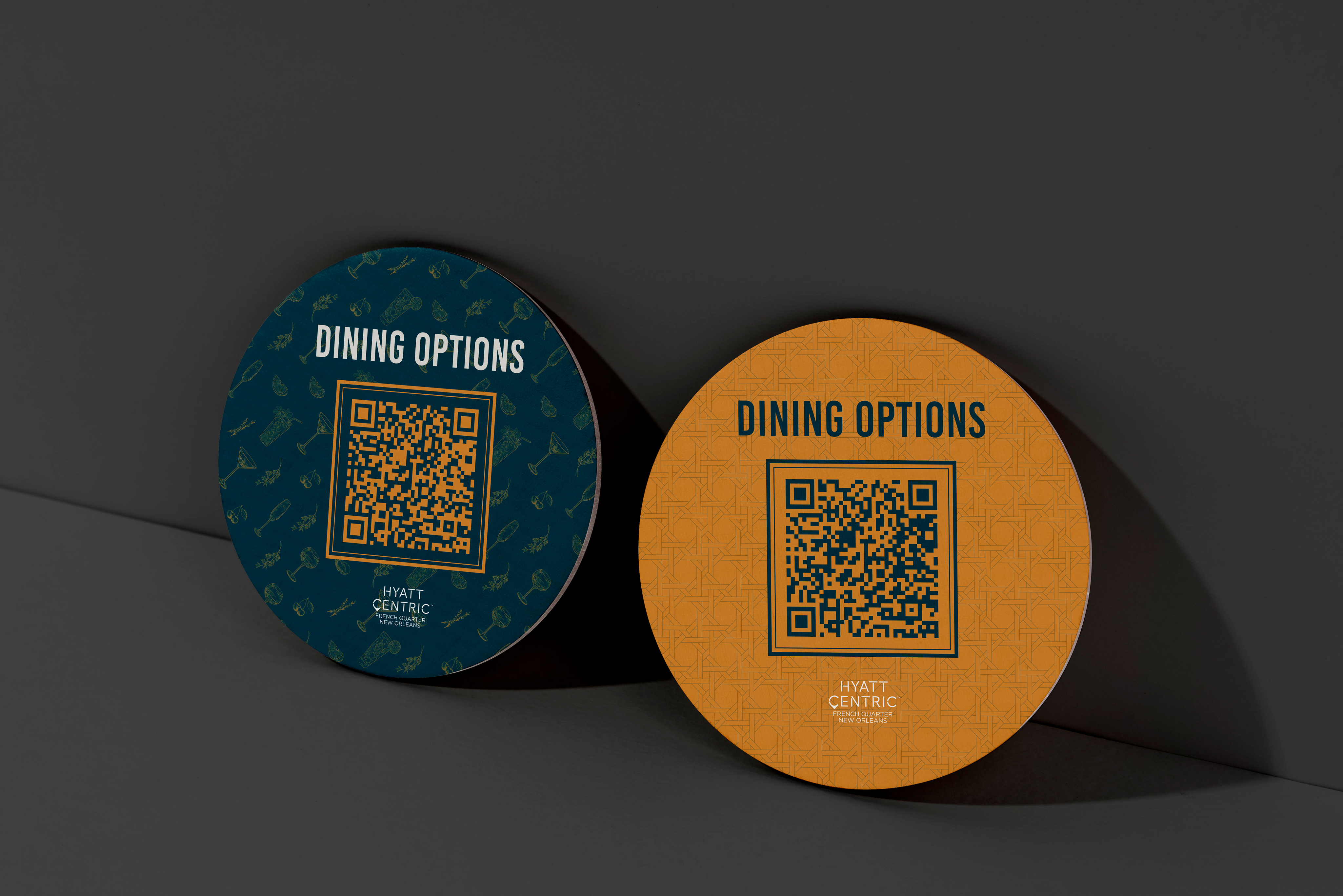 Two round coasters with QR codes labeled "Dining Options" and "Hyatt Centric" placed on a dark surface.