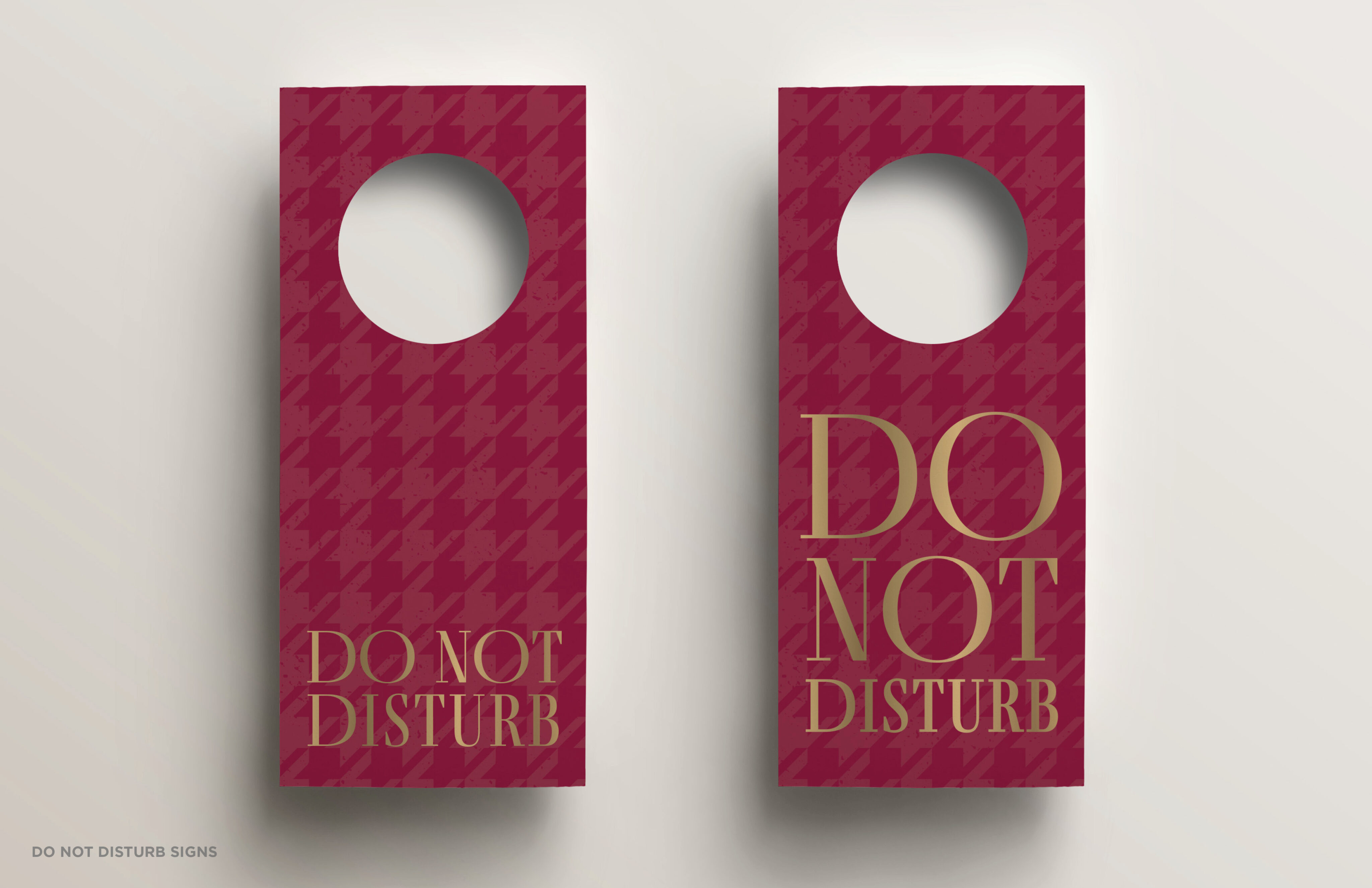 Two red door hangers with a geometric pattern, both displaying the text "DO NOT DISTURB" in gold capital letters.