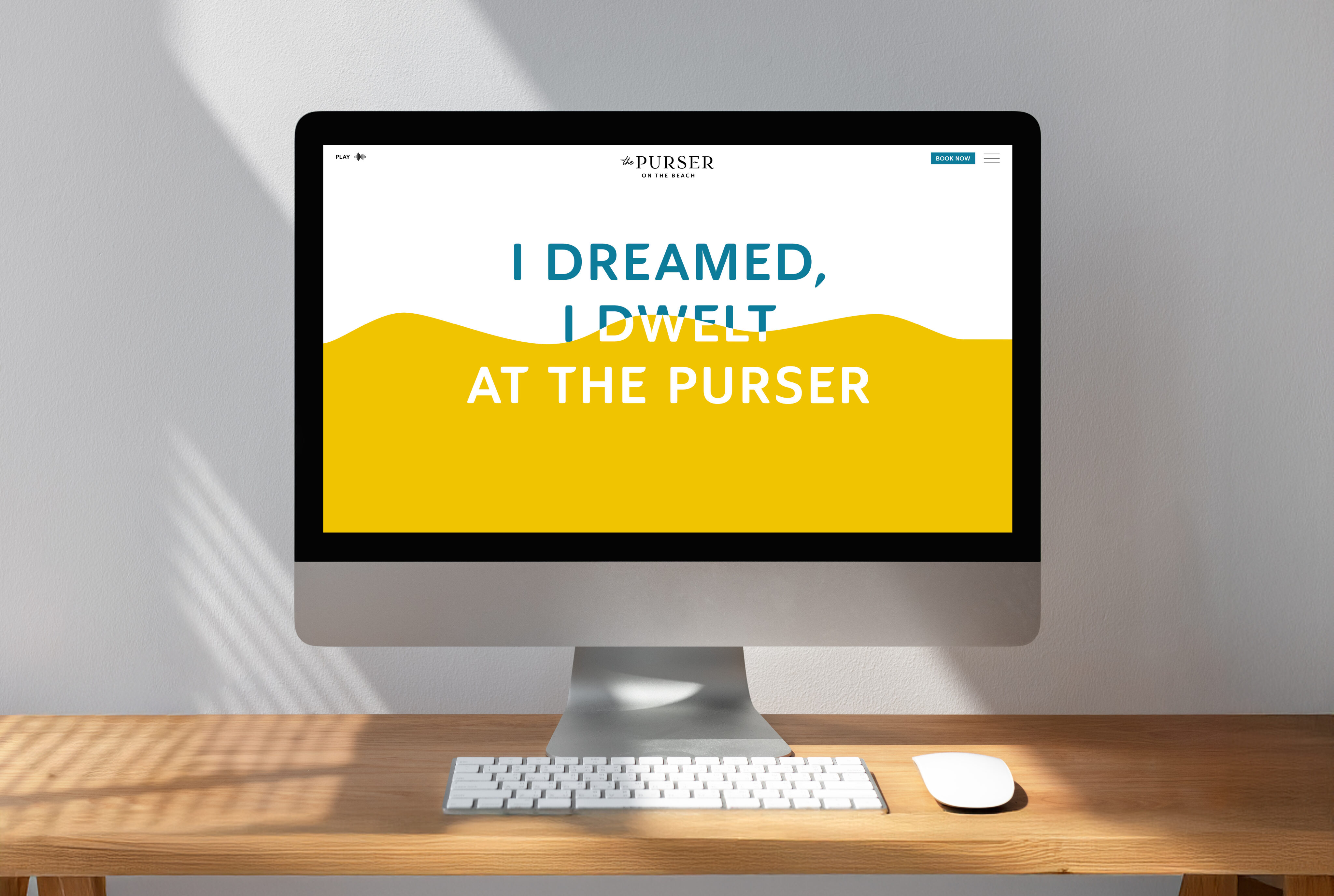 A desktop computer on a wooden desk displays a website with the text "I DREAMED, I DWELT AT THE PURSER" on a white and yellow background.