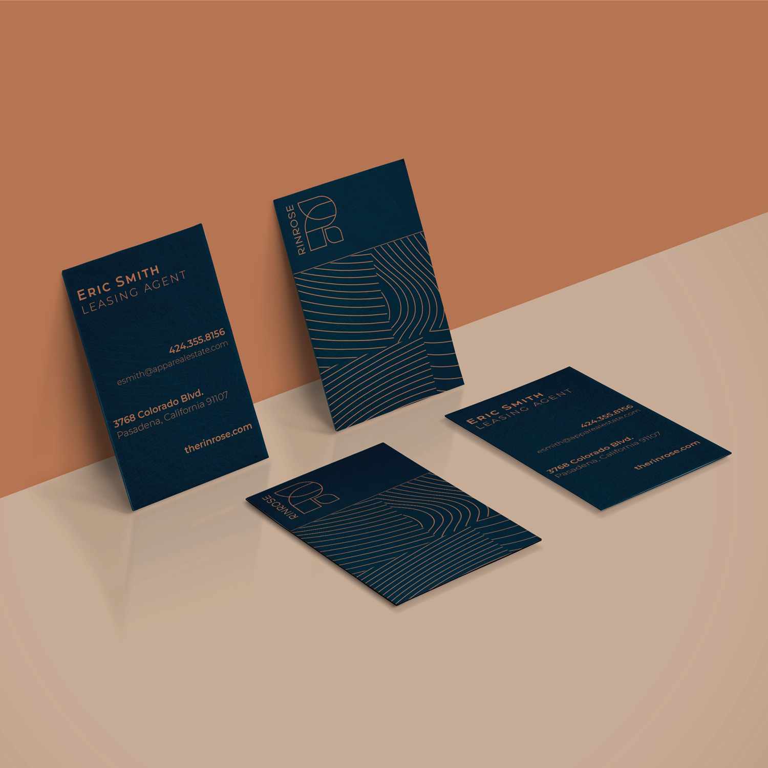 Four navy blue business cards with minimalist geometric lines and white text are displayed on a two-tone brown and beige surface.