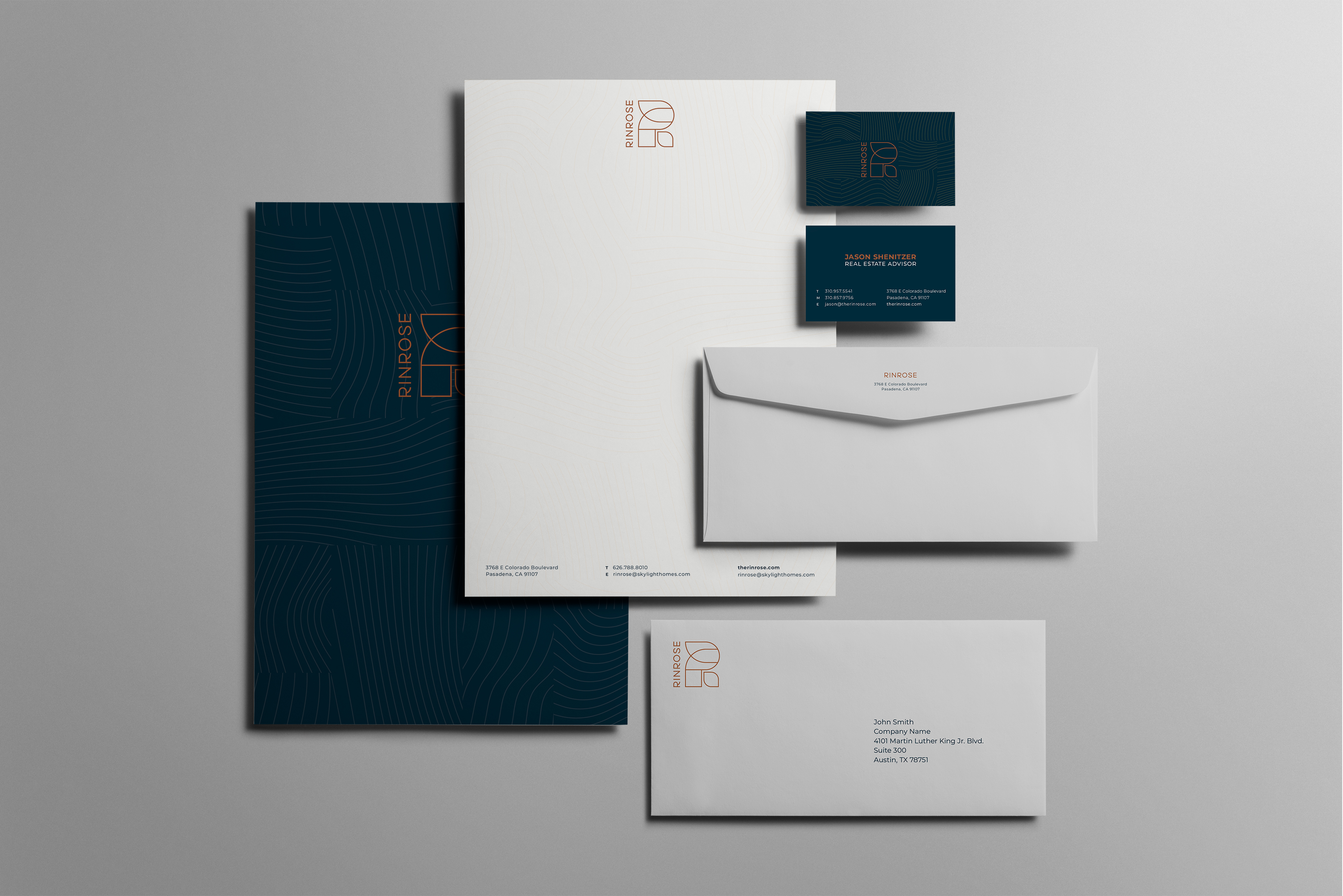 A branded stationery set including business cards, letterhead, envelopes, and a folder, arranged on a light grey surface.