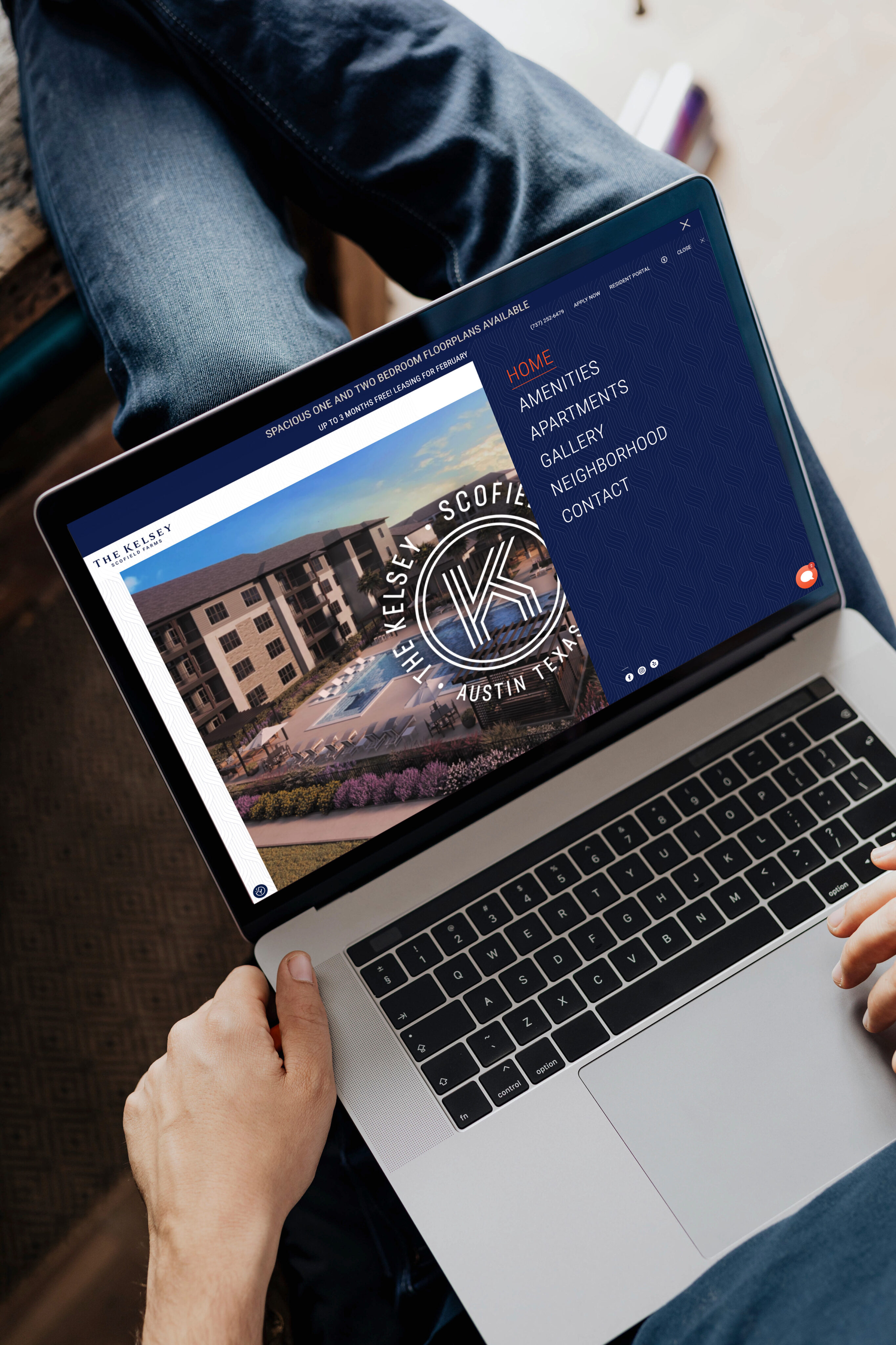 A person holds a laptop displaying a website for The Kelsey at Scofield, an apartment complex in Austin, Texas, with a navigation menu visible.