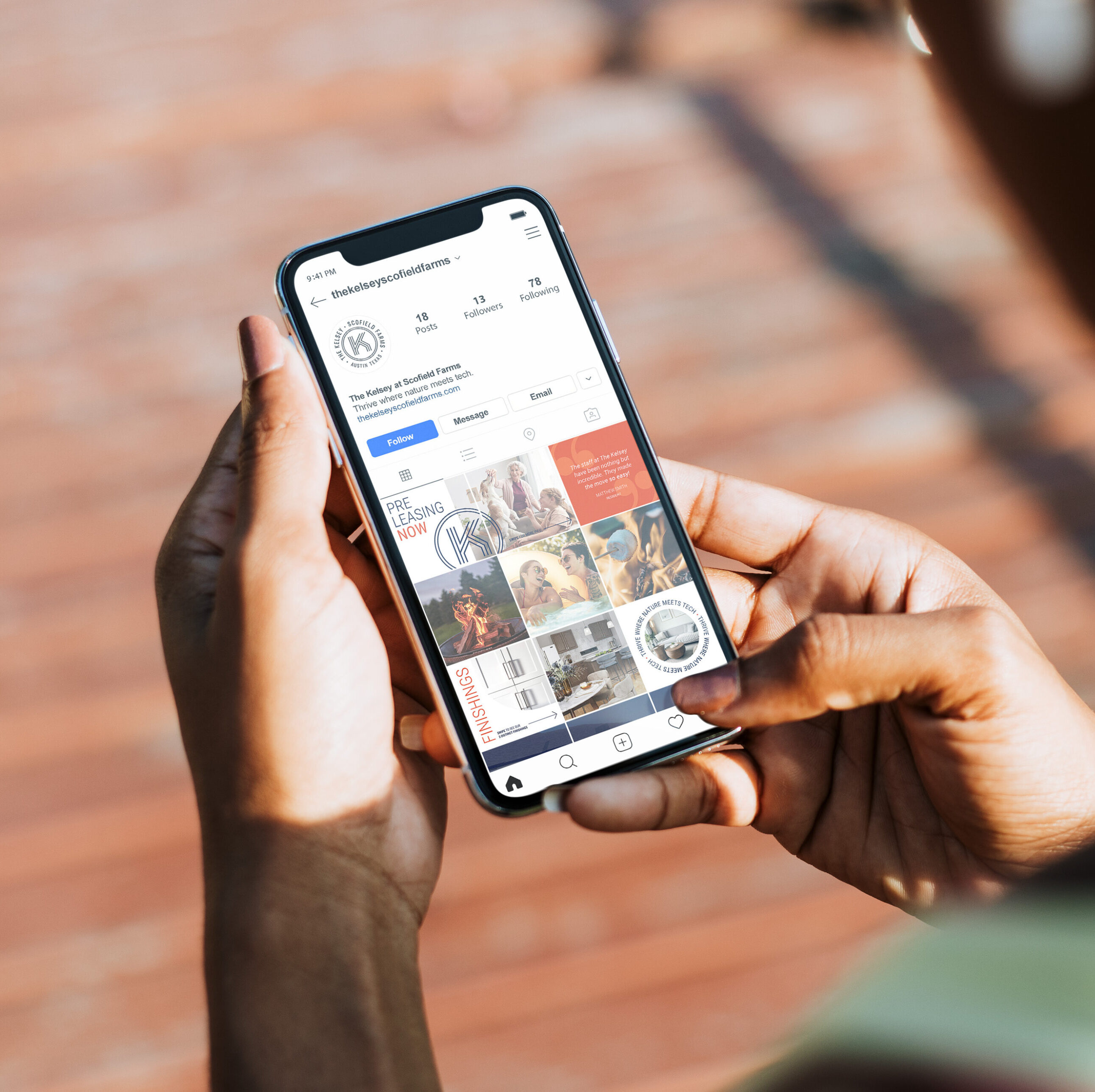 A person holding a smartphone browses an Instagram profile displaying posts, stories, and profile details on the screen.
