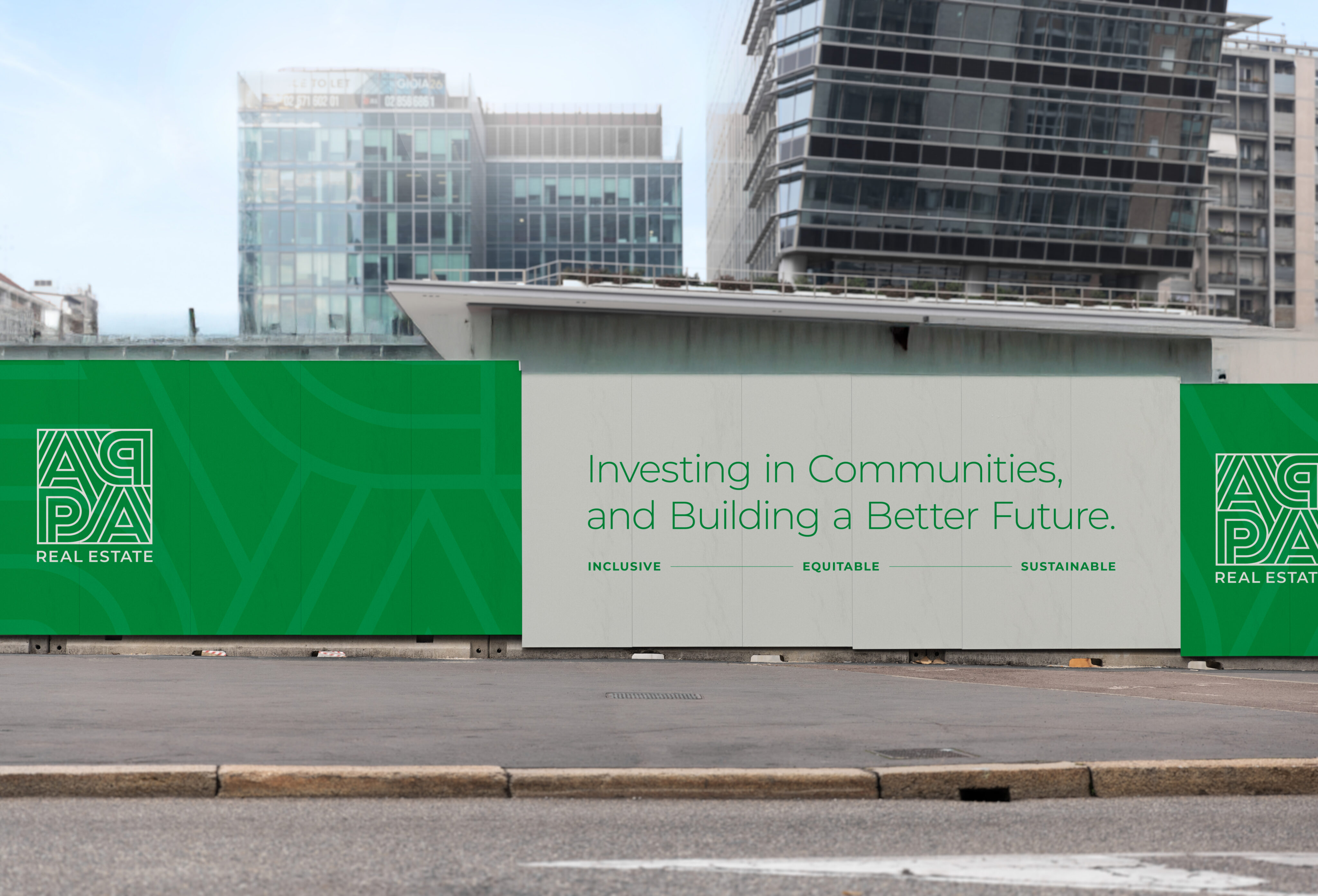 A construction site fence displays AGPA Real Estate branding and the slogan, “Investing in Communities, and Building a Better Future. Inclusive. Equitable. Sustainable.” Modern buildings in background.