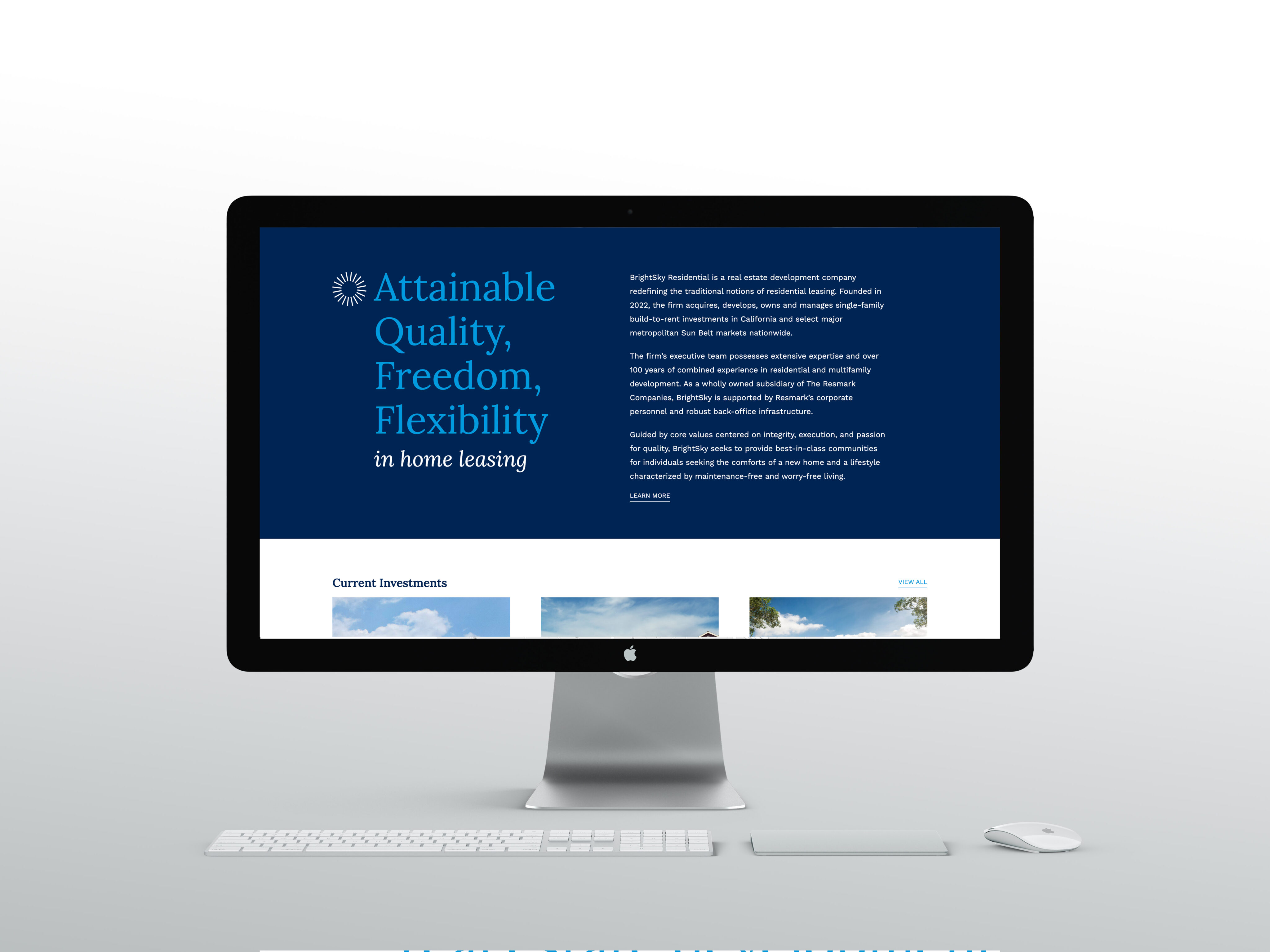 A desktop computer displays a website about home leasing, showing text on attainable quality, freedom, and flexibility, with a keyboard and mouse on a white desk.