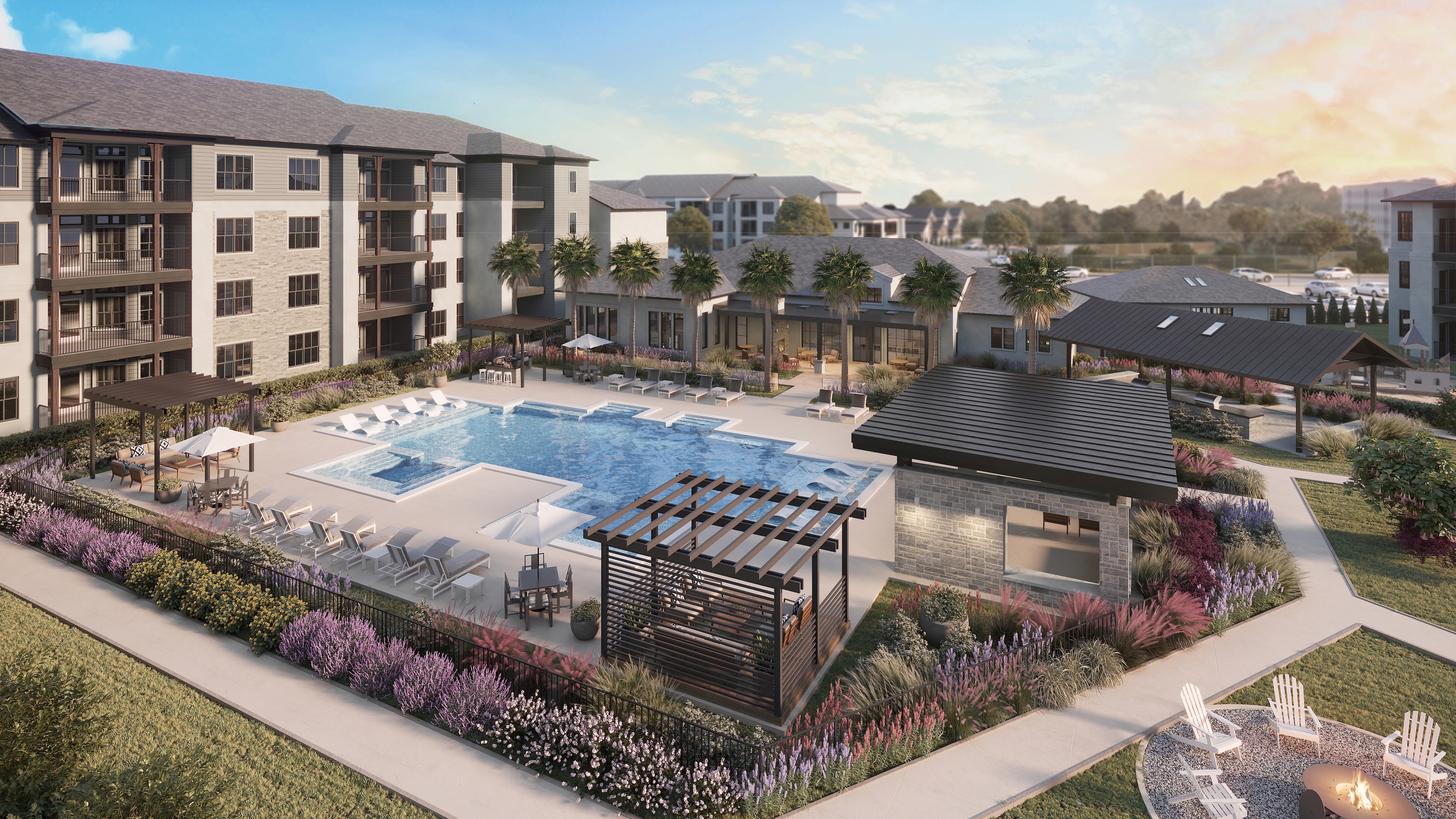 A modern apartment complex features a central outdoor pool, lounge areas with umbrellas, landscaped gardens, and a fire pit at sunset.